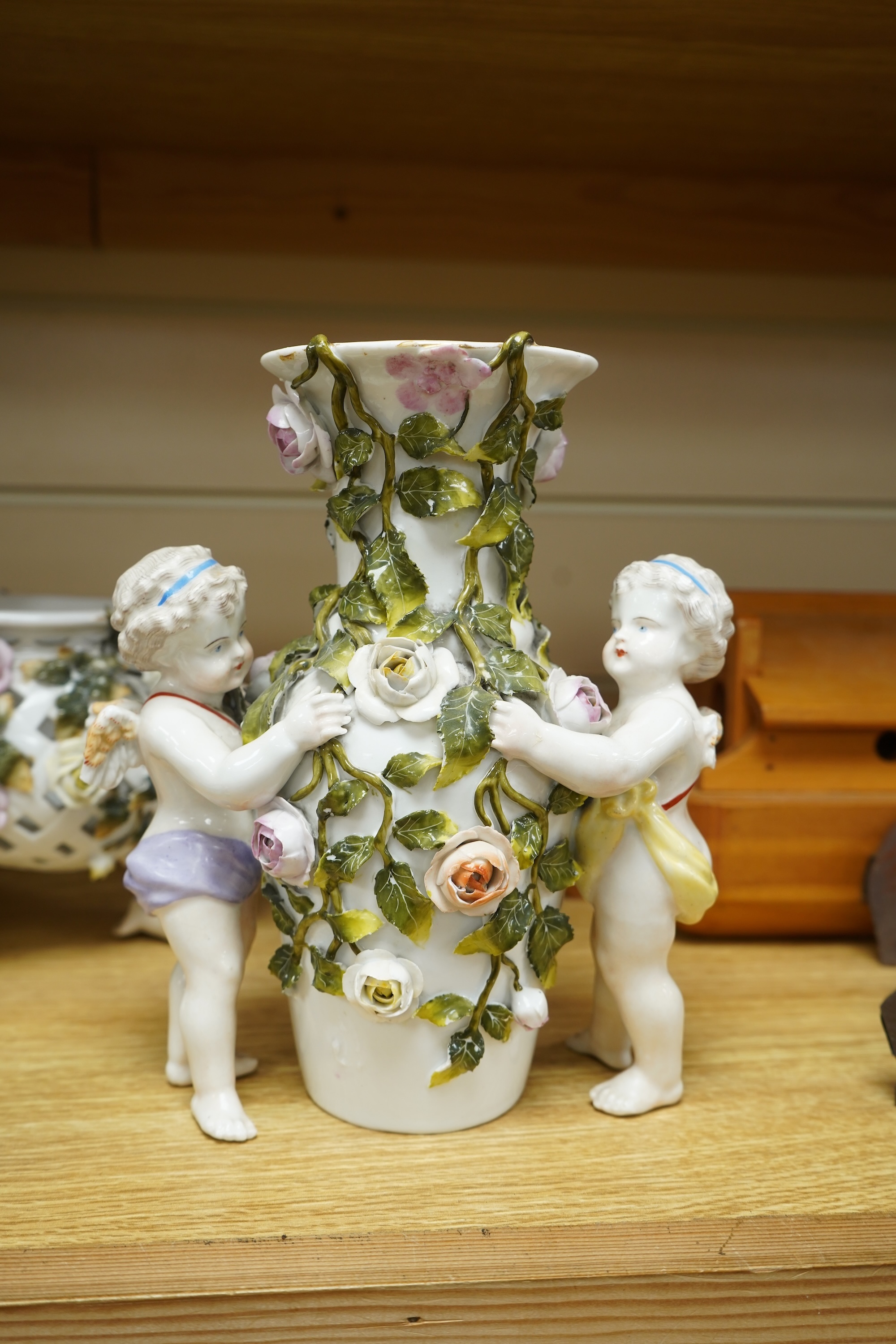 A German flower encrusted porcelain figural candelabrum, 30cm high, a cherub jardiniere and a cherub vase, all encrusted